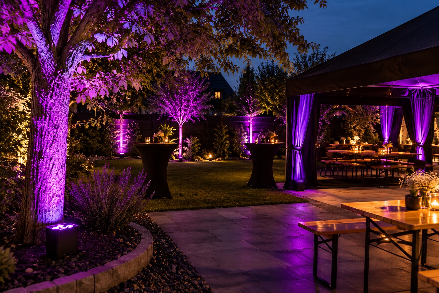 Gartenparty am Abend mit violett beleuchteten Bäumen, Sitzplätzen und Zelt